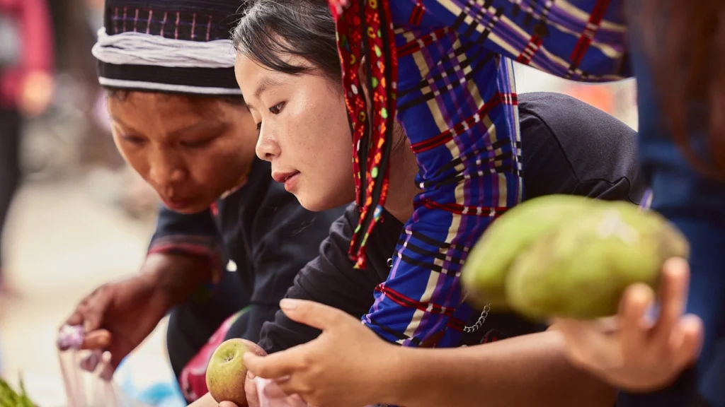 A young Vietnamese woman selects fruit at a local market.