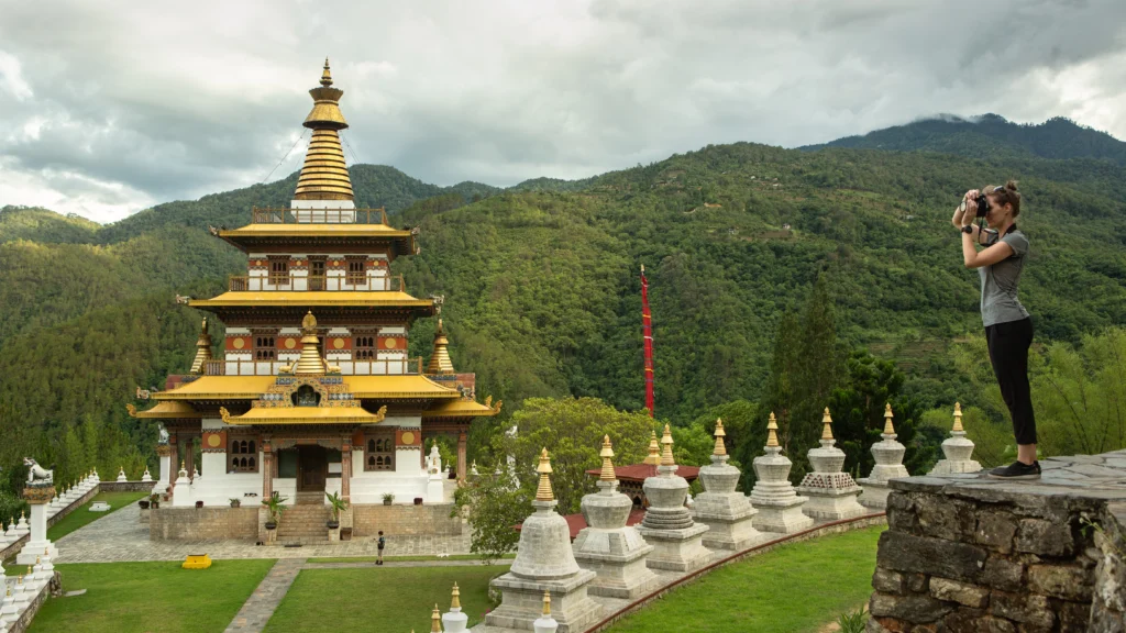 A woman takes a photograph of a temple in Bhutan.